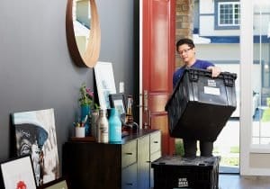 man in blue polo shirt carrying the box