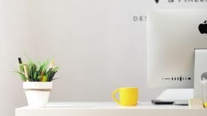 yellow ceramic mug beside iMac