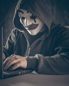 A man at a laptop, with a mask on