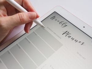 person writing on the white ipad