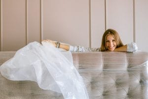 A woman wrapping her couch in plastic wrap.