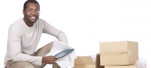 a man standing near cardbaord boxes holding an item in his hands to pack for an emergency move