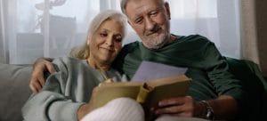 an elderly couple enjoying memories from a photo album as one of the ways to pass time when you are helping your senior grandparents pack their home