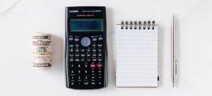 a stack of money next to a black calculator and a notepad as essentials for preparing for your spring relocation