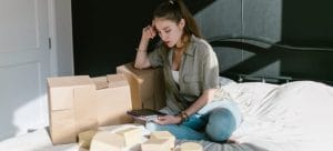 Girl with boxes sitting and looking at a tablet.
