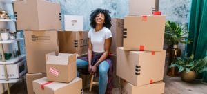 a woman sitting between cardboard boxes after learning which foods should you pack for moving