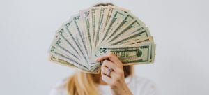 a woman holding a large amount of money in front of her face