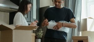 A man and a woman using packing supplies, which are important when packing your living room when moving to Paradise