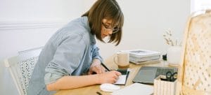 Picture of a woman with glasses making notes in order to avoid forgetting some of the commonly forgotten things during a move