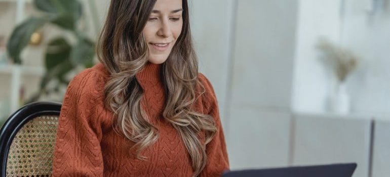 A young woman checking her laptop and looking for some of the best long distance movers Las Vegas offers