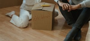 two persons sitting around a cardboard box and talking about unpacking tips for moving to Las Vegas