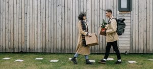 A couple walking on the grass while holding boxes